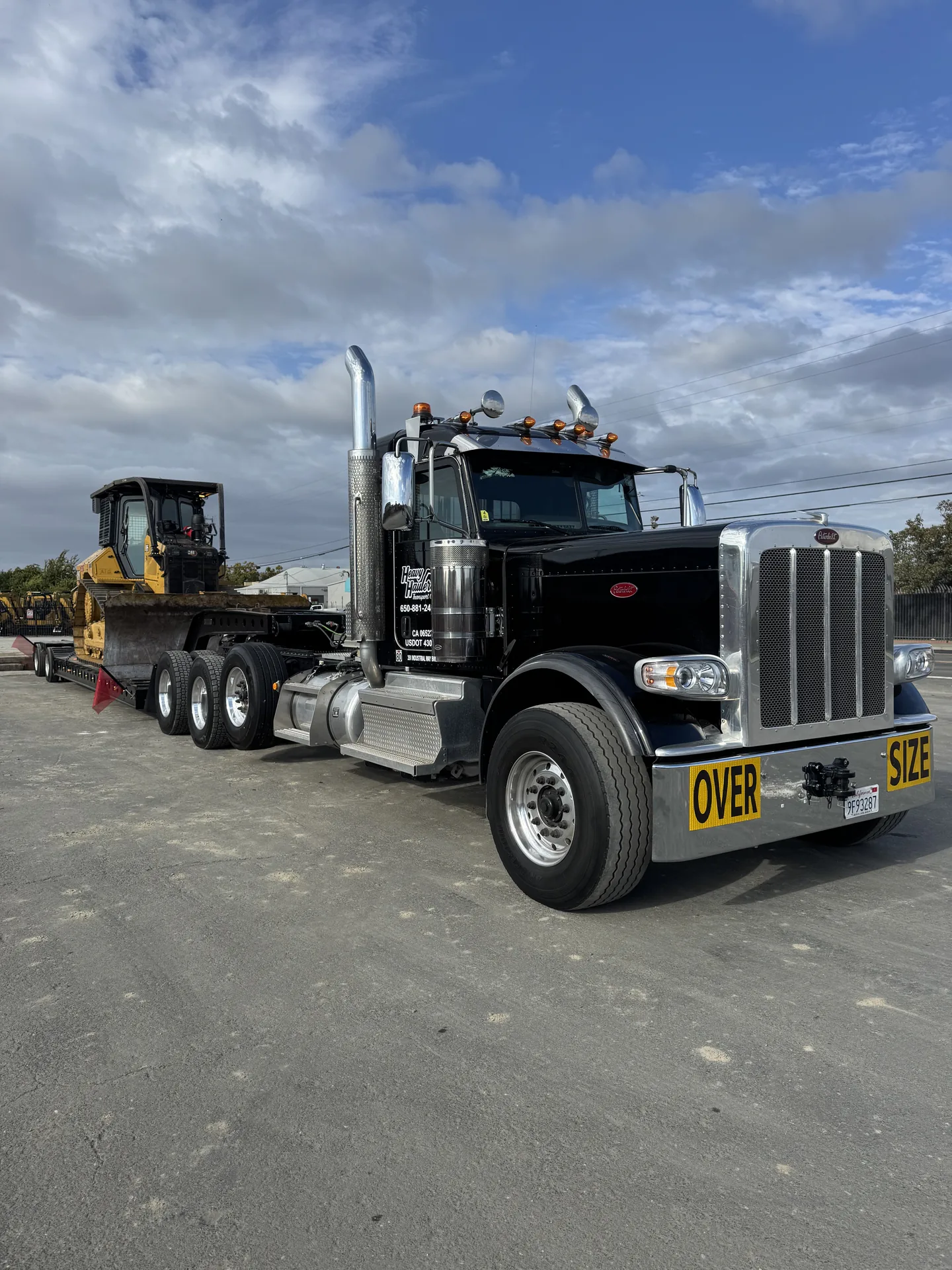 Heavy Haulers oversize Peterbilt truck hauling CAT equipment on lowboy — dramatic low-angle shot
