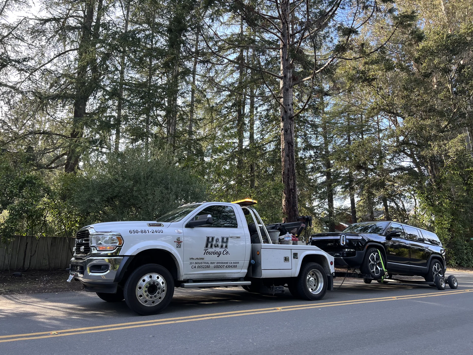 Heavy Tow Pro recovering a black Cadillac Escalade SUV on a tree-lined residential road in the Bay Area